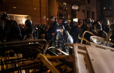 Police officers walk through a barricade put up by demonstrators during a protest in Hong Kong