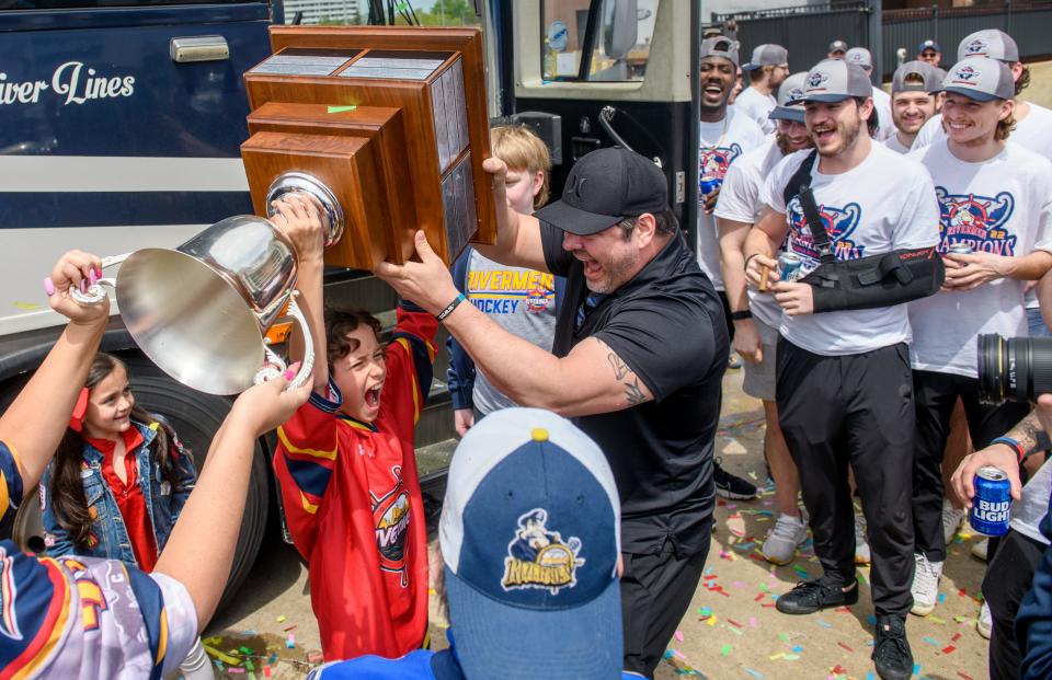 Peoria Rivermen head coach Jean-Guy Trudel helps his stepson Jimmy Spratt raise the President's Cup while his daughter Chloe, lower left, waits her turn Wednesday, May 4, 2022 upon the team's return to the Peoria Civic Center from their SPHL championship run in Roanoke, Virginia.