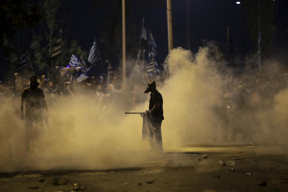 Protesters stand amid tear gas smoke during clashes with police at the northern Greek city of Thessaloniki, Saturday, Sept. 8, 2018. Greek police say about 6,000 protesters have tried to reach a venue where prime minister Alexis Tsipras is due to give a keynote address on the economy later Saturday and were pushed back with tear gas and stun grenades. (AP Photo/Dimitris Tosidis)