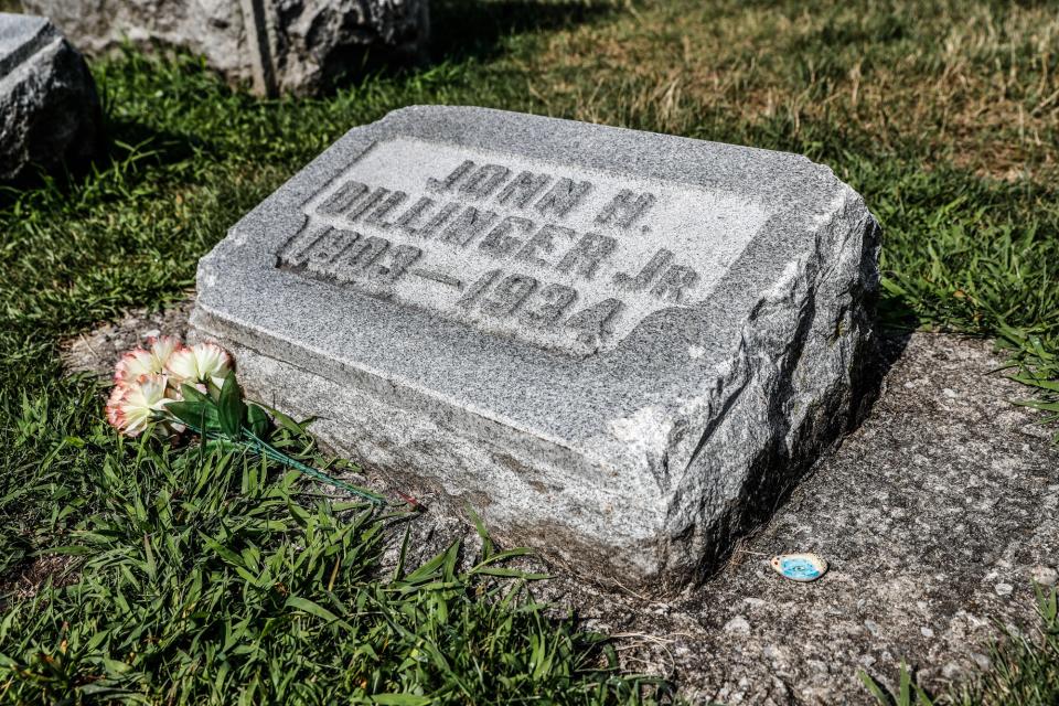 The grave of John Dillinger Jr. sits inside the walls of Crown Hill Cemetery in Indianapolis. Dillinger's smaller headstone sits in the family plot marked by a larger headstone. Small chunks of the stone, which may have been replaced once, have been chipped off by visitors over the years.