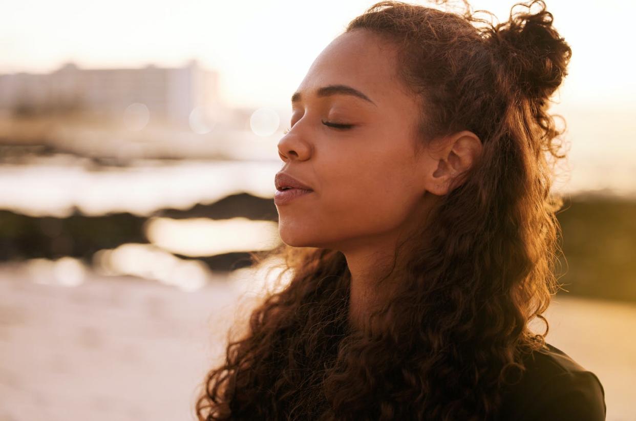 Practicing mindfulness doesn't have to mean being removed from the world. <a href="https://www.gettyimages.com/detail/photo/shot-of-an-attractive-young-woman-sitting-alone-on-royalty-free-image/1317735408?phrase=mindfulness&adppopup=true" rel="nofollow noopener" target="_blank" data-ylk="slk:PeopleImages/iStock via Getty Images Plus;elm:context_link;itc:0;sec:content-canvas" class="link ">PeopleImages/iStock via Getty Images Plus</a>