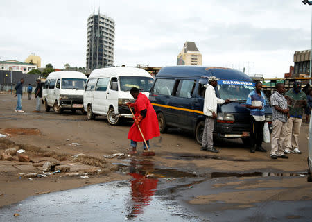 A worker sweeps in front of minibus taxi operators in Harare, Zimbabwe, January 17, 2019. REUTERS/Philimon Bulawayo