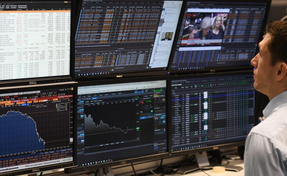 A trader looks at screens of financial data 