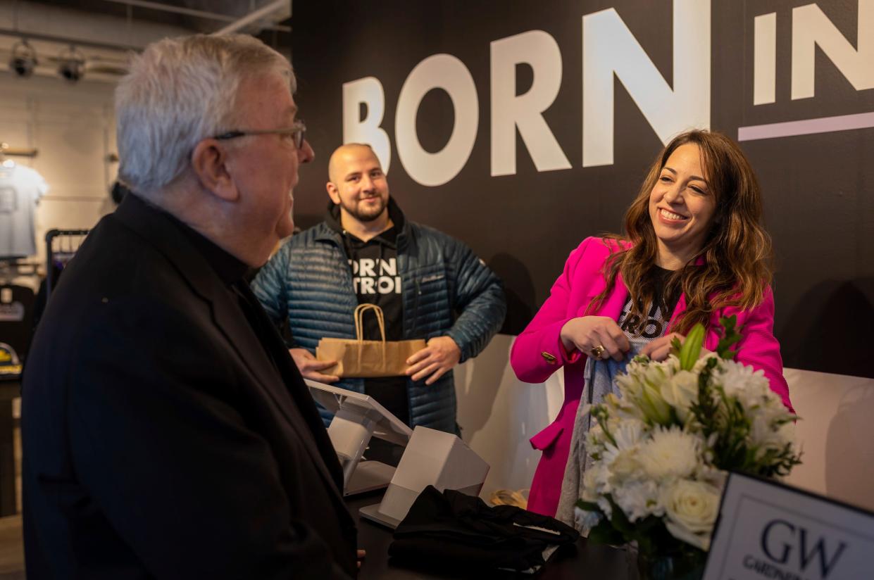 The Rev. Charles Kosanke, left, is greeted by Kameel Sabak, center, and Amy Cosola, as he buys a shirt inside the Born in Detroit storefront pop-up in Detroit on Friday, March 15, 2024. The Detroit pop-up location is Born In Detroit's first dedicated storefront.