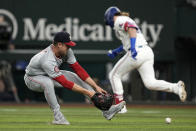 Washington Nationals starting pitcher MacKenzie Gore, left, reaches down to field a grounder by Texas Rangers' Davis Wendzel as he runs to first base in the fourth inning of a baseball game in Arlington, Texas, Tuesday, April 30, 2024. Wendzel was out at first on the play. (AP Photo/Tony Gutierrez)