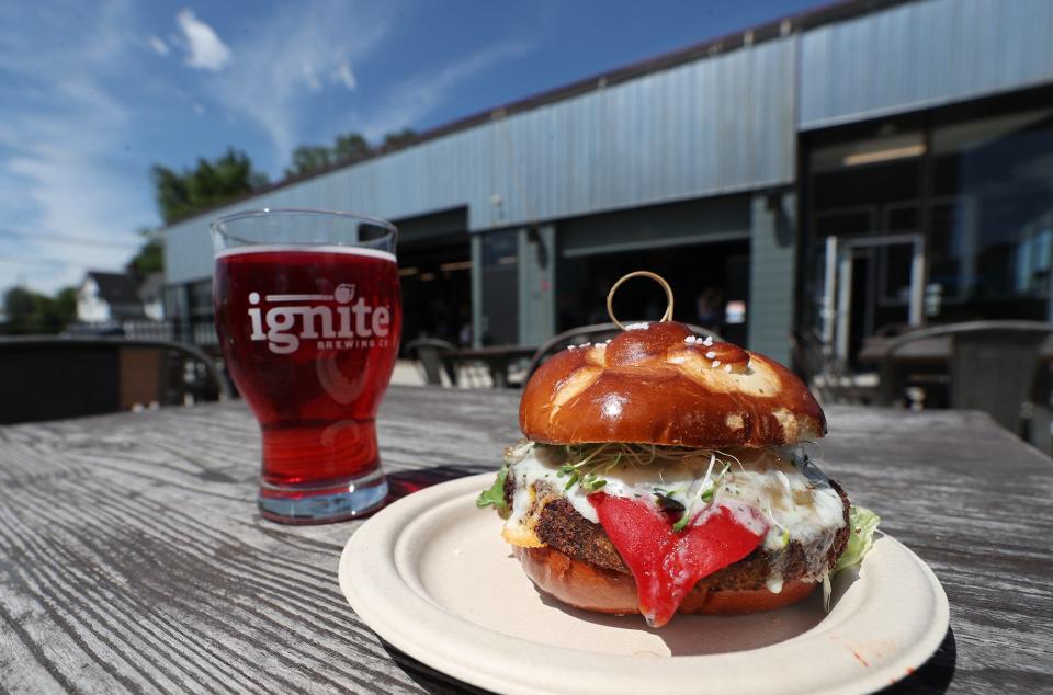 A glass of Maba Mama, a strawberry and hibiscus margarita gose, and a Farmer's Burger, a veggie burger with more veggies on top, on a pretzel bun by Crafted Eats at Ignite.