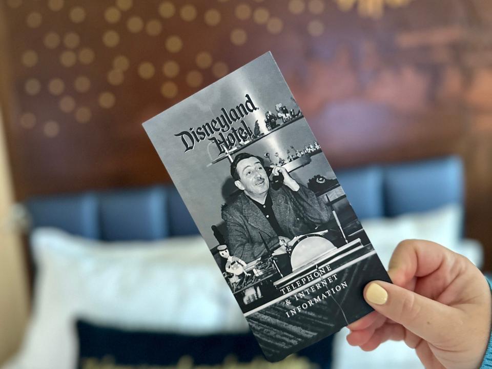 hand holding a walt disney card in a bedroom at the disneyland hotel