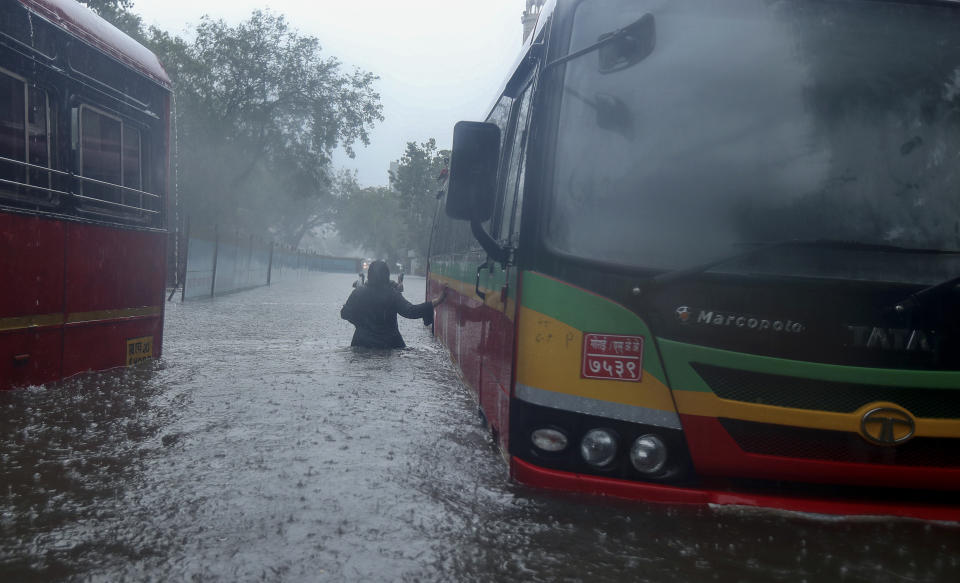 A woman walks through a waterlogged street in Mumbai, India, Monday, May 17, 2021. Cyclone Tauktae, roaring in the Arabian Sea was moving toward India's western coast on Monday as authorities tried to evacuate hundreds of thousands of people and suspended COVID-19 vaccinations in one state. (AP Photo/Rafiq Maqbool)