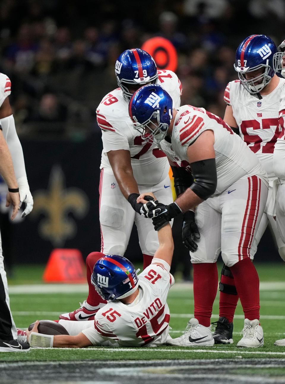 New York Giants quarterback Tommy DeVito (15) is helped up by teammate Ben Bredeson (68) after being sacked during the second half of an NFL football game against the New Orleans Saints Sunday, Dec. 17, 2023, in New Orleans. (AP Photo/Gerald Herbert)