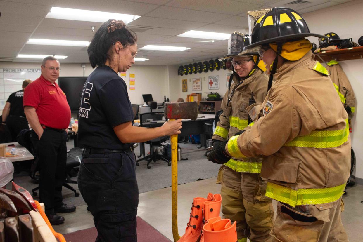 Topeka Fire Department training officer Chelsea Reese, middle, hands off an ax to recruits Alyssa Conway, second from right, and BreAnna Droge, far right, at the TFD headquarters.