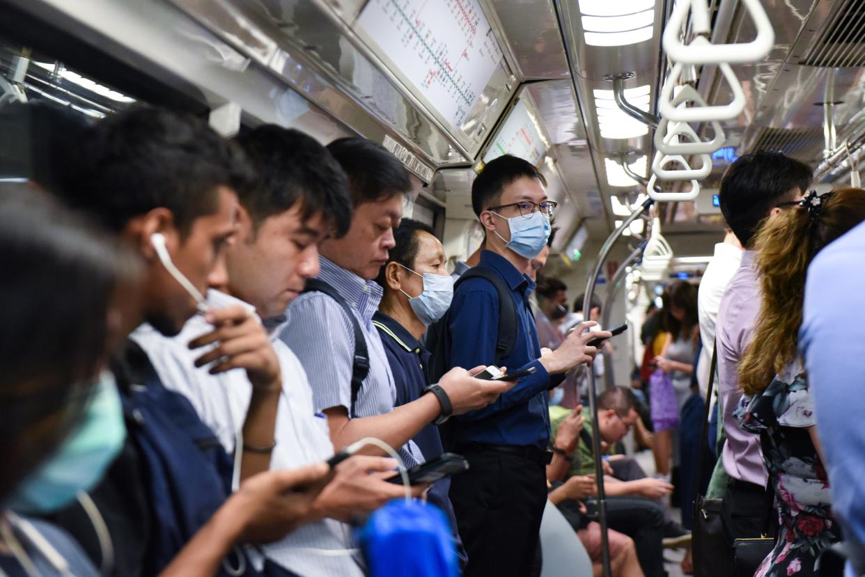 Commuters wear face masks on the Mass Rapid Transit train as a preventive measure against the COVID-19 coronavirus in Singapore on March 18, 2020. (Photo by Catherine LAI / AFP) (Photo by CATHERINE LAI/AFP via Getty Images)