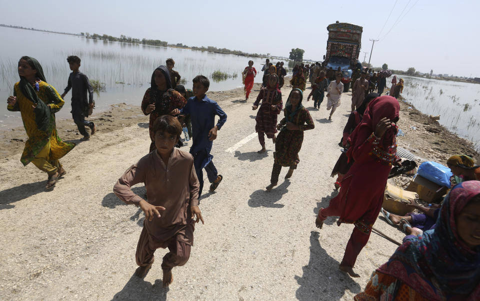 Victims of heavy flooding from monsoon rains crowd run to receive relief aid from the Pakistani Army in the Qambar Shahdadkot district of Sindh Province, Pakistan, Friday, Sept. 9, 2022. U.N. Secretary-General Antonio Guterres appealed to the world for help for cash-strapped Pakistan after arriving in the country Friday to see the climate-induced devastation from months of deadly record floods. (AP Photo/Fareed Khan)