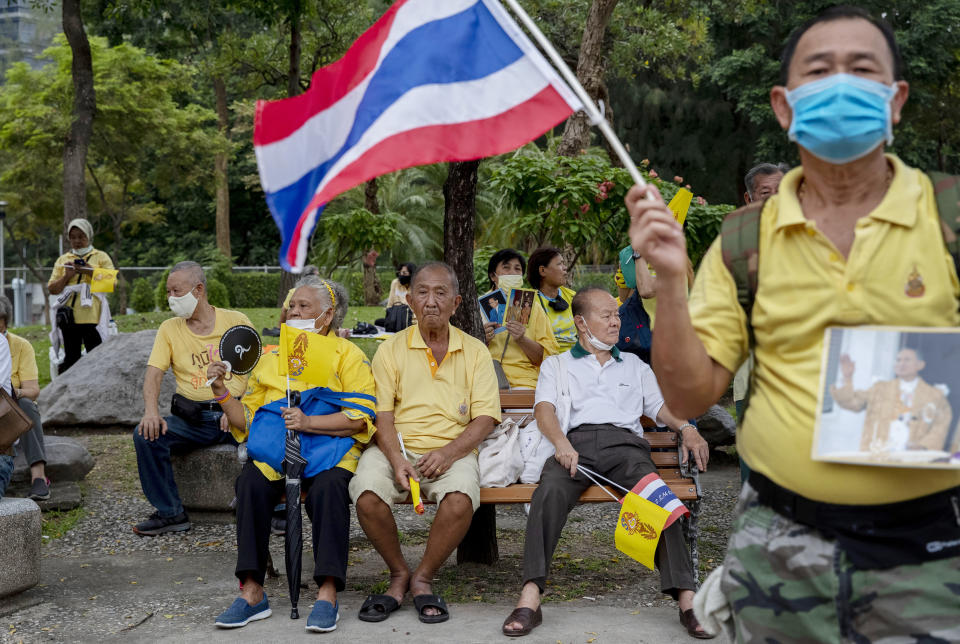 Elderly supporters of the Thai monarchy sit and watch as others wave Thai national flags and sing during a rally at Lumphini park in central Bangkok, Thailand Tuesday, Oct. 27, 2020. Hundreds of royalists gathered to oppose pro-democracy protesters' demands that the prime minister resign, constitution be revised and the monarchy be reformed in accordance with democratic principles. (AP Photo/Gemunu Amarasinghe)