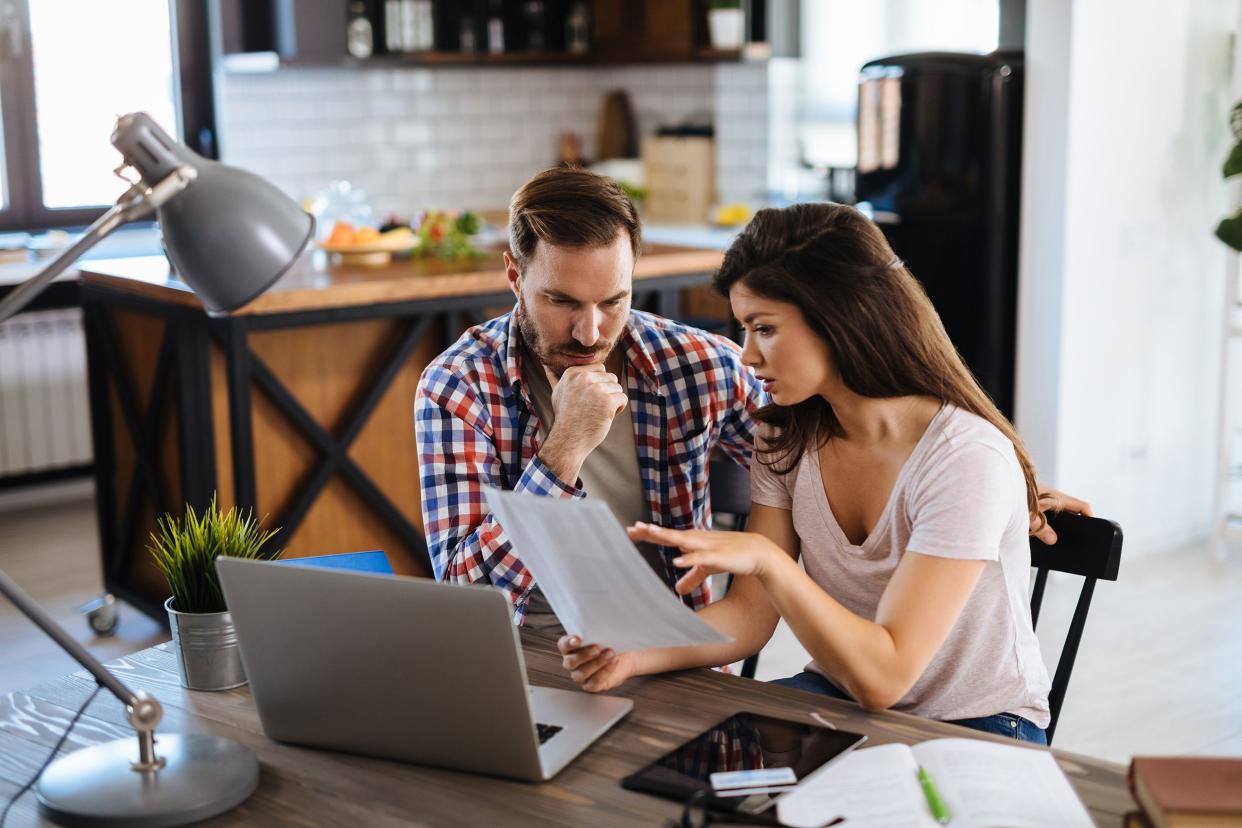 frustrated couple checking bills at home using laptop