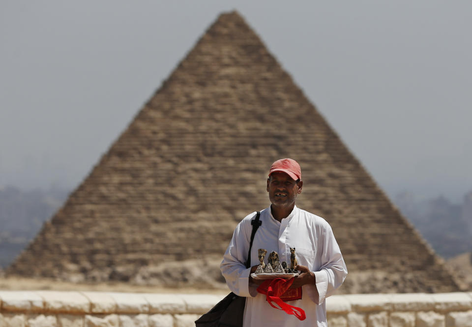 In this Saturday, Sept. 7, 2013 photo, a vendor offers souvenirs for sale to tourists at the historical site of the Giza Pyramids, near Cairo, Egypt. Before the 2011 revolution that started Egypt's political roller coaster, sites like the pyramids were often overcrowded with visitors and vendors, but after a summer of coup, protests and massacres, most tourist attractions are virtually deserted to the point of being serene. (AP Photo/Lefteris Pitarakis)