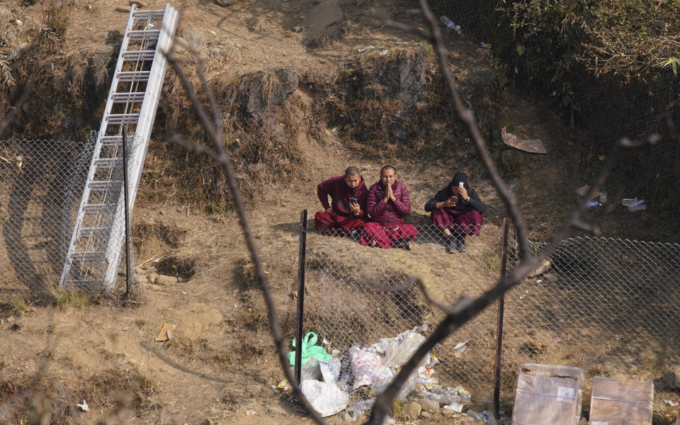 Buddhist monks pray for the plane crash victims, at the crash site, in Pokhara, Nepal, Wednesday, Jan.18, 2023. Nepalese authorities are returning to families the bodies of plane crash victims and are sending the aircraft's data recorder to France for analysis as they try to determine what caused the country's deadliest air accident in 30 years. The flight plummeted into a gorge on Sunday while on approach to the newly opened Pokhara International Airport in the foothills of the Himalayas, killing all 72 aboard.(AP Photo/Yunish Gurung)