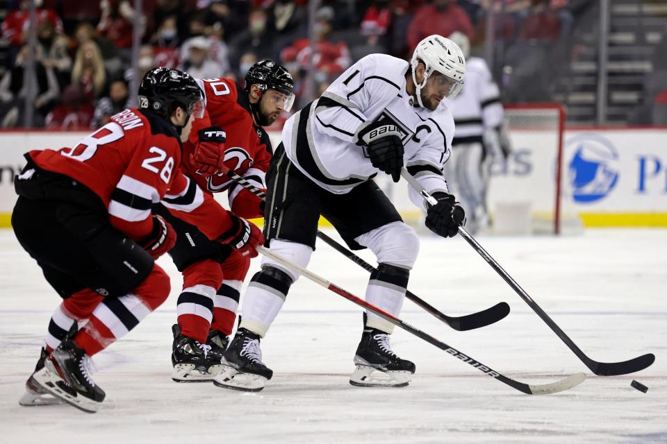 Los Angeles Kings center Anze Kopitar (11) passes the puck in front of New Jersey Devils defenseman Damon Severson during the first period of an NHL hockey game Sunday, Jan. 23, 2022, in Newark.