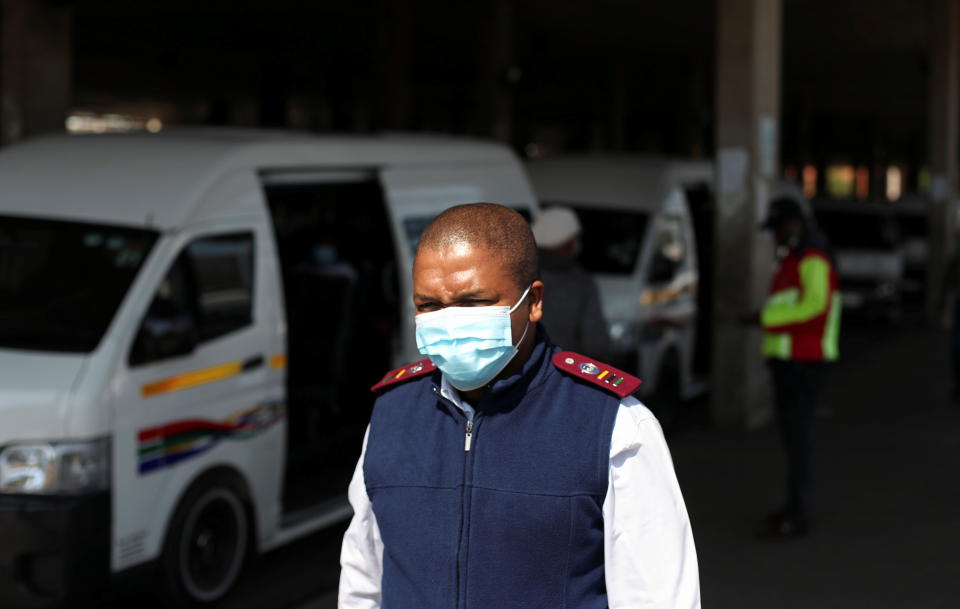 A health worker wears a face mask as he walks past a taxi after the announcement of a British ban on flights from South Africa because of the detection of a new coronavirus disease (COVID-19) variant, in Soweto, South Africa, November 26, 2021. REUTERS/Siphiwe Sibeko