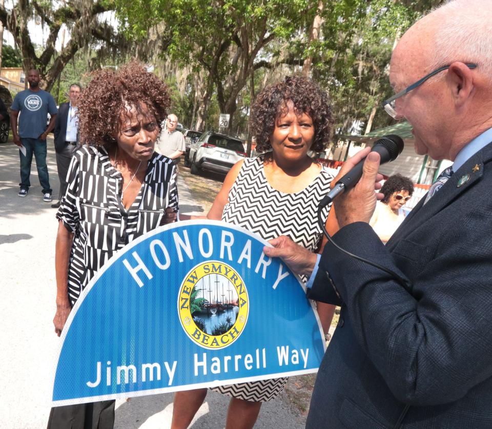 New Smyrna Beach Mayor Fred Cleveland presents a replica of the new street sign renaming Duss Street as Honorary Jimmy Harrell Way to Harrell's daughters Brenda Jones and Linda Herring, Thursday, April 27, 2023, during a ceremony outside the Mary S. Harrell Black Heritage Museum in New Smyrna Beach.