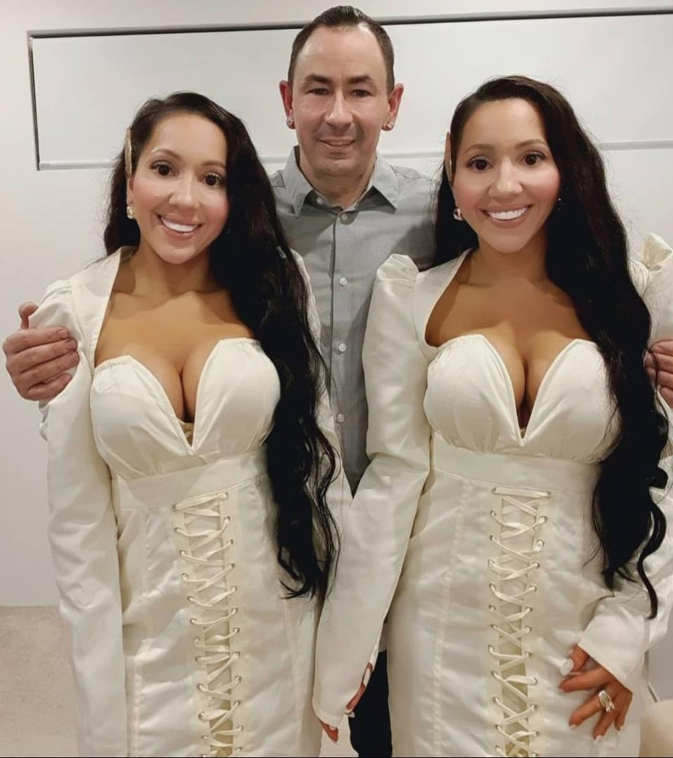 Identical twins Anna and Lucy DeCinque wearing matching white dresses with their shared partner, Ben Byrne