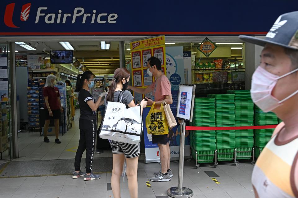 People waiting to enter a supermarket have their identity documents checked by staff before they can enter the premises, as a protective measure against the spread of the COVID-19 novel coronavirus, in Singapore on May 2, 2020. (Photo by Roslan RAHMAN / AFP) (Photo by ROSLAN RAHMAN/AFP via Getty Images)