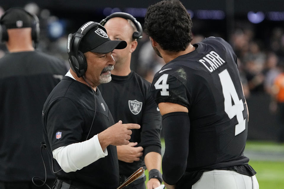 Las Vegas Raiders interim head coach Rich Bisaccia speaks with quarterback Derek Carr (4) during the second half of an NFL football game against the Philadelphia Eagles, Sunday, Oct. 24, 2021, in Las Vegas. (AP Photo/Rick Scuteri)