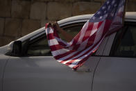 An Israeli supporter of U.S. President Donald Trump for re-election waves an American flag from her car as she headed for a rally outside of the U.S. Embassy, in Jerusalem, Tuesday, Oct. 27, 2020. (AP Photo/Maya Alleruzzo)