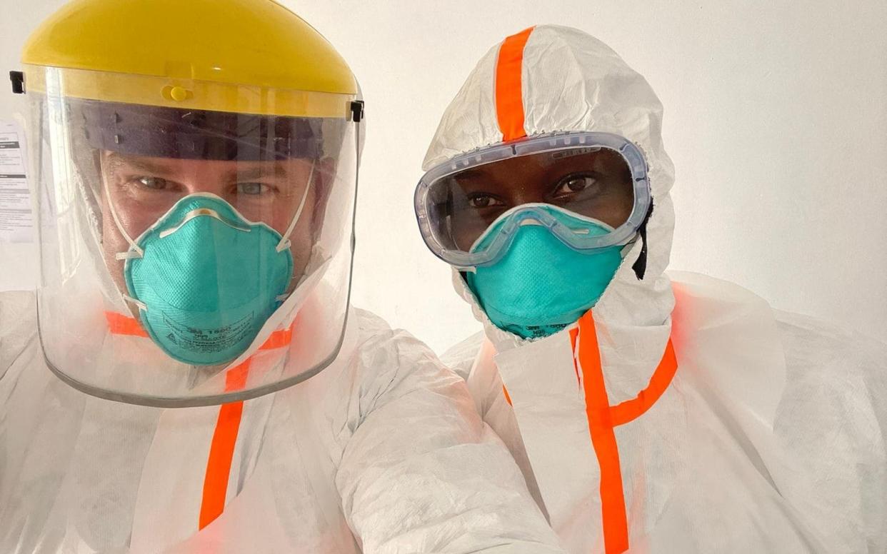 Dr Tom Fletcher (left) and a Ugandan colleague in PPE as they head into a treatment centre - Via Tom Fletcher