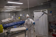 An employee of the new Nurse Isabel Zendal Hospital disinfects a box of the COVID-19 ICU ward in Madrid, Spain, Monday, Jan. 18, 2021. As the coronavirus curve of contagion turned increasingly vertical after Christmas and New Year's, the Zendal has been busy. On Monday, 392 virus patients were being treated, more than in any other hospital in the Madrid region. (AP Photo/Bernat Armangue)