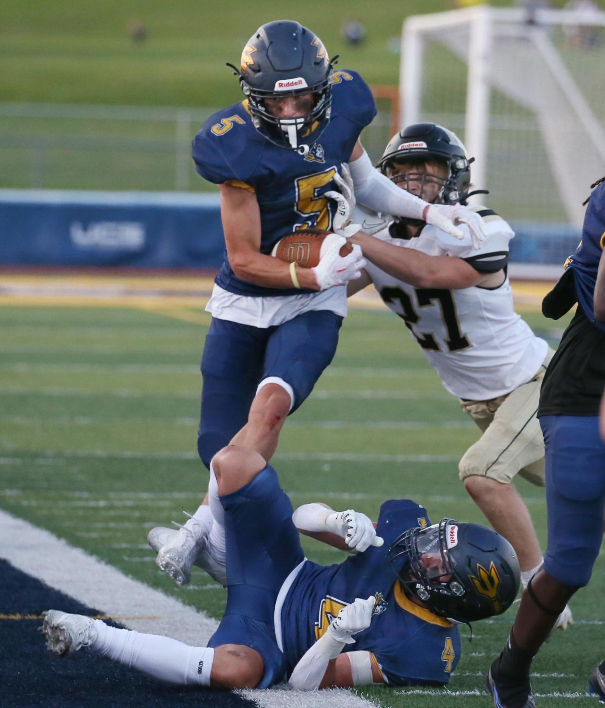 Victor's Adam Ruffalo hurdles over teammate Jameson Ricigliano as he is pushed out of bounds along the sideline by Rush-Henrietta's Zachary Erne.