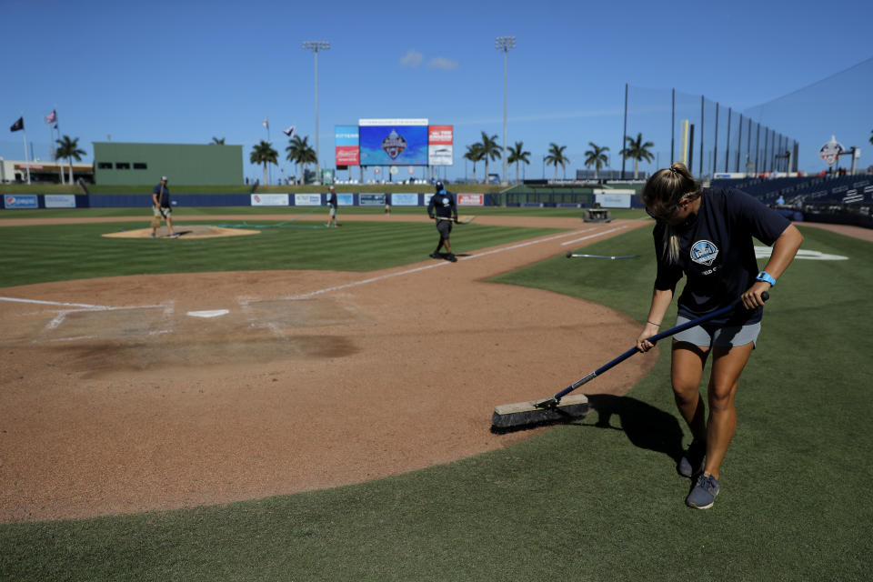 A grounds crew member sweeps the home plate area at FITTEAM Ballpark of The Palm Beaches after a large crowd watched a spring training baseball game between the New York Yankees and the Washington Nationals, Thursday, March 12, 2020, in West Palm Beach, Fla. Major League Baseball is delaying the start of its season by at least two weeks because of the coronavirus outbreak and has suspended the rest of its spring training game schedule. (AP Photo/Julio Cortez)