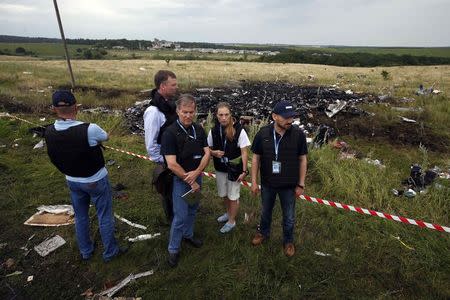 Organisation for Security and Cooperation in Europe (OSCE) monitors stand at the site of Thursday's Malaysia Airlines Boeing 777 plane crash near the settlement of Grabovo in the Donetsk region July 18, 2014. REUTERS/Maxim Zmeyev