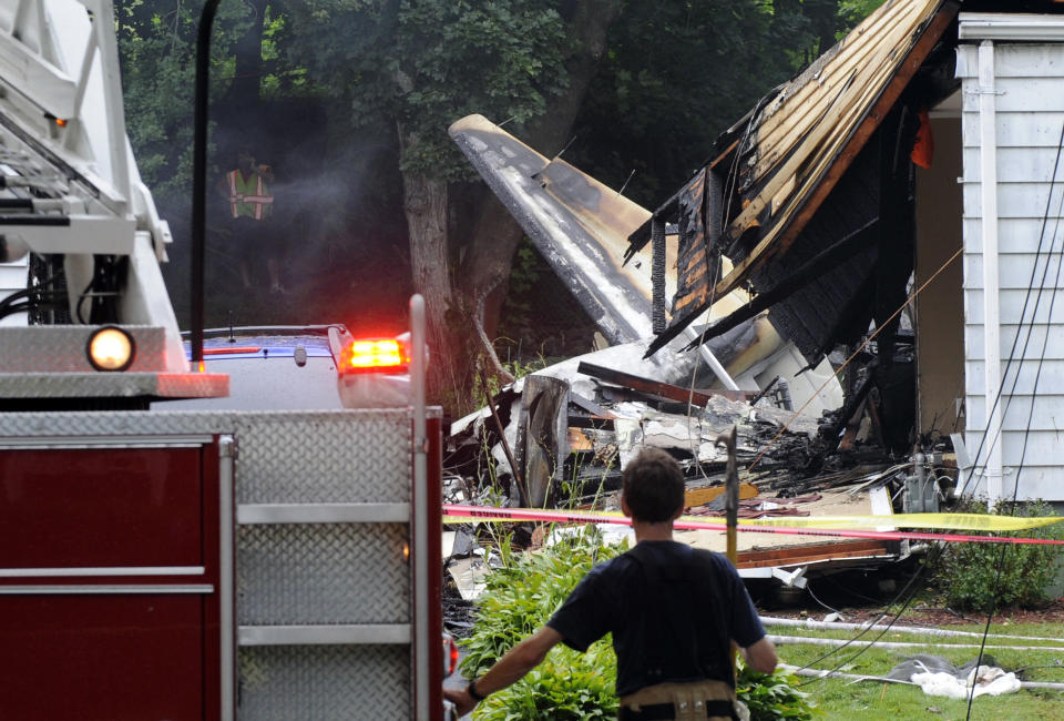 A firefighter surveys the scene of a small plane crash, Friday, Aug. 9, 2013, in East Haven, Conn. The multi-engine, propeller-driven plane plunged into a working-class suburban neighborhood near Tweed New Haven Airport, on Friday. (Fred Beckham/AP)