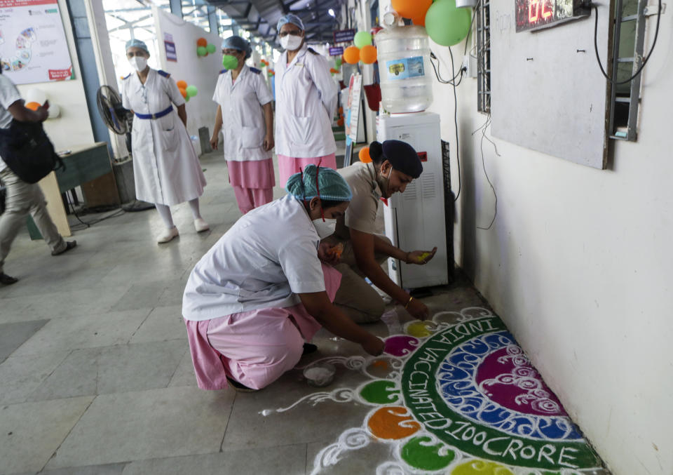 Health workers make a design on the floor as they celebrate India administering 1 billion doses of COVID-19 vaccine, at Rajawadi hospital in Mumbai, India, Thursday, Oct. 21, 2021. India has administered 1 billion doses of COVID-19 vaccine, passing a milestone for the South Asian country where the delta variant fueled its first crushing surge this year. (AP Photo/Rajanish Kakade)