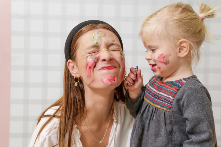 A small kid drawing on her face and the babysitter's dace with lipstick