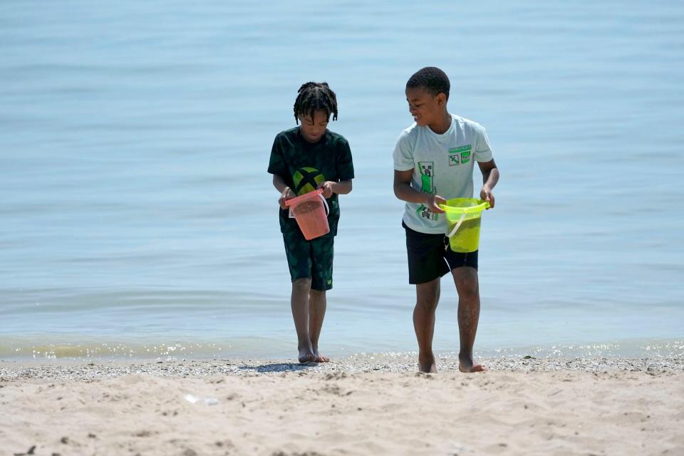 Jason Carter (left), 7, and his brother, Jayceon Beamon, 9, who were with their mother, Lameesha Beamon, of Milwaukee, carry pails of sand and water from the shoreline at Bradford Beach on North Lincoln Memorial Drive in Milwaukee on Thursday, June 1, 2023.