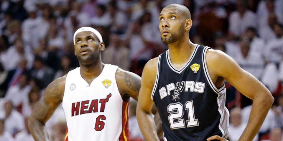 LeBron James and Tim Duncan stand next to each other and look up during a game.