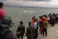 Emergency crews await boats returning with rescued passengers from the capsized ship off Ormoc City, central Philippines