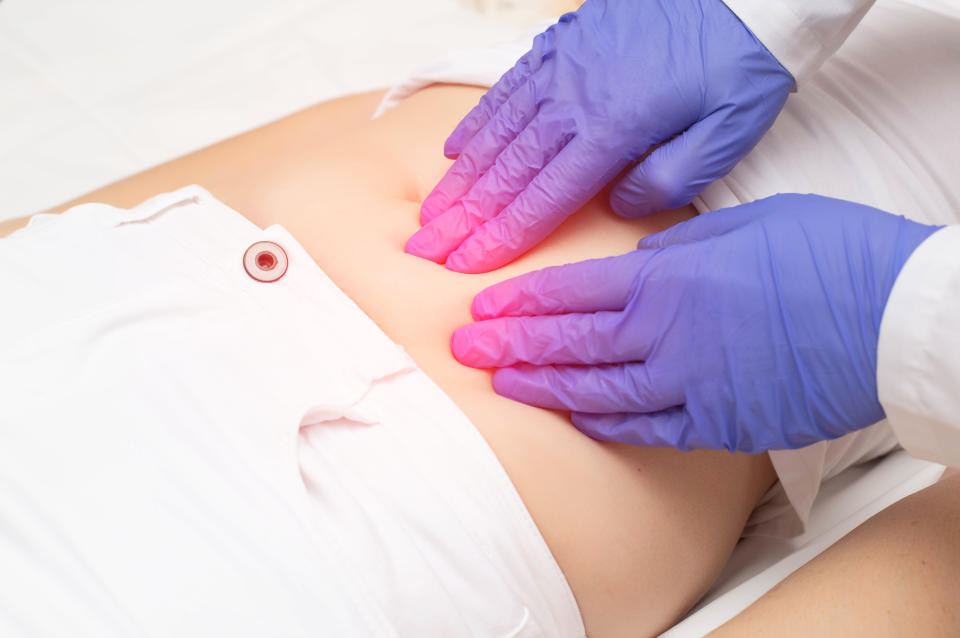 A doctor touches the lower abdomen of a girl who has pain and inflammation of the reproductive system