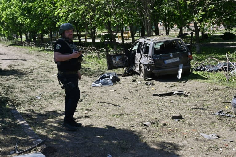 Un policier ukrainien près d'une voiture détruite par une frappe russe à Zlotchiv, dans la région de Kharkiv, le 1er mai 2024 (SERGEY BOBOK)