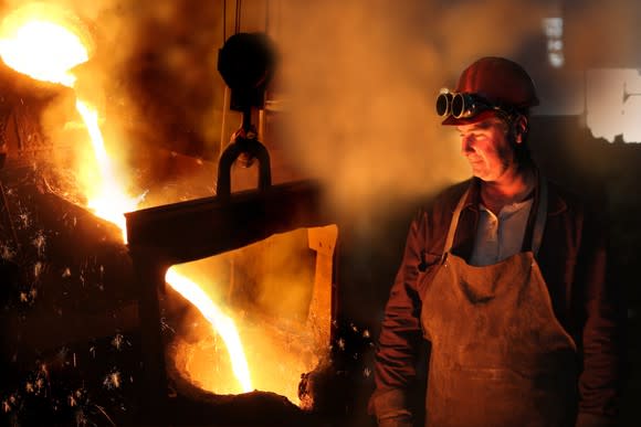 A man standing in a steel mill with molten steel flowing