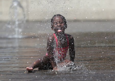 A girl plays with water in a fountain during a hot summer day in Brussels