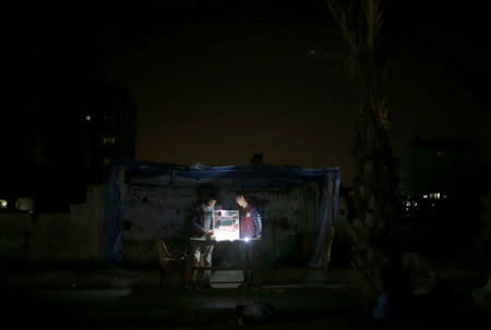 A Palestinian vendor uses battery-powered lights as he sells cigarettes during power cut at Shati refugee camp in Gaza City. REUTERS/Mohammed Salem