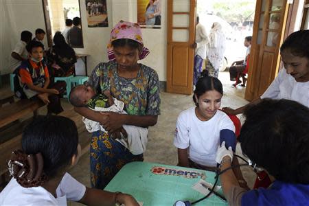 A Rohingya woman shows her baby to a nurse as another woman is examined by a doctor from the Ministry of Health at a hospital near the Dar Paing camp for internally displaced people in Sittwe, Rakhine state, April 24, 2014. REUTERS/Minzayar