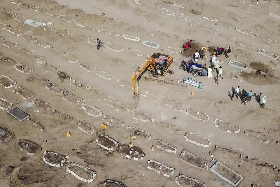 In this May 21, 2020, photo, grave diggers bury a body at Radwan Cemetery in Aden, Yemen. At the cemetery in Yemen’s largest southern city, dozens of fresh graves are a testament to a spike in deaths amid the coronavirus pandemic. The cemetery workers who bury them don’t know what killed the newly deceased. But there’s no denying that there's been an increasing number of people getting sick in the port city of Aden — likely from the coronavirus. (AP Photo)