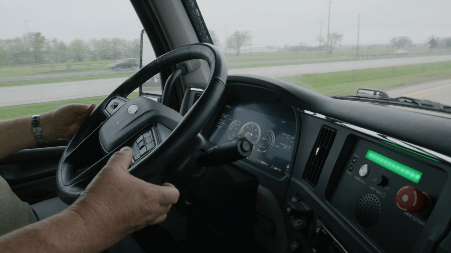 A backup driver in a self-driving Aurora Innovation big rig with his hands near, but not on the steering wheel (Courtesy: Aurora Innovation)