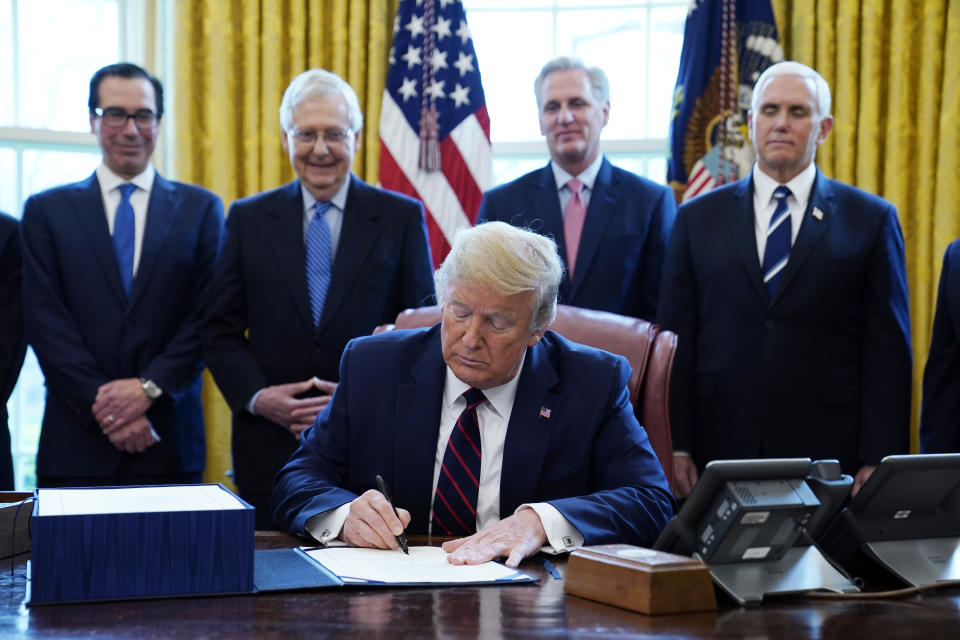 FILE - President Donald Trump signs the coronavirus stimulus relief package, at the White House in Washington, on March 27, 2020, accompanied by, from left, Treasury Secretary Steven Mnuchin, Senate Majority Leader Mitch McConnell of Ky., House Minority Kevin McCarthy of Calif., and Vice President Mike Pence. An Associated Press analysis published on Monday, June 12, 2023, found that fraudsters potentially stole more than $280 billion in COVID-19 relief funding; another $123 billion was wasted or misspent. Combined, the loss represents a jarring 10 percent of the total $4.2 trillion the U.S. government has so far disbursed in COVID-relief aid. (AP Photo/Evan Vucci, File)