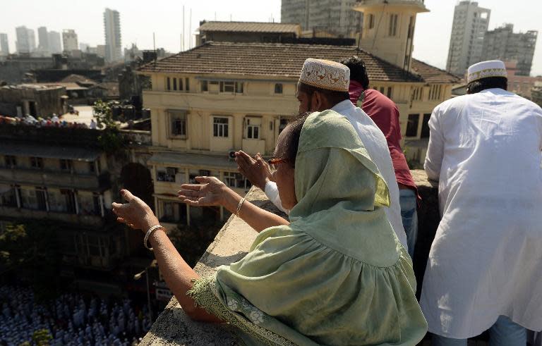 Indian Bohra Muslims pray as the funeral procession of their spiritual leader Syedna Mohammed Burhanuddin in Mumbai on January 18, 2014