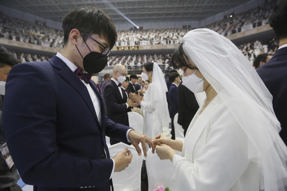 A couple wearing face masks exchanges their rings in a mass wedding ceremony at the Cheong Shim Peace World Center in Gapyeong, South Korea, Friday, Feb. 7, 2020. (AP Photo/Ahn Young-joon)