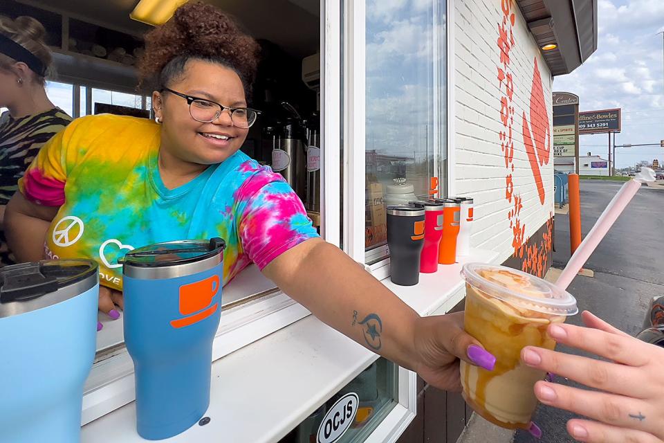 Orange Cup Java Station employee Amanda Davis hands a drink order to a customer at the shop's 1426 N. Henderson St. location on  April 23, 2022.